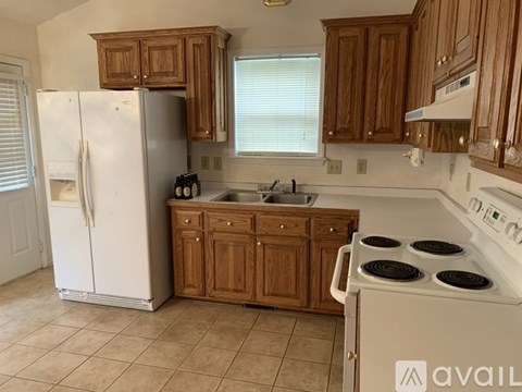 A kitchen with white appliances and wooden cabinets.