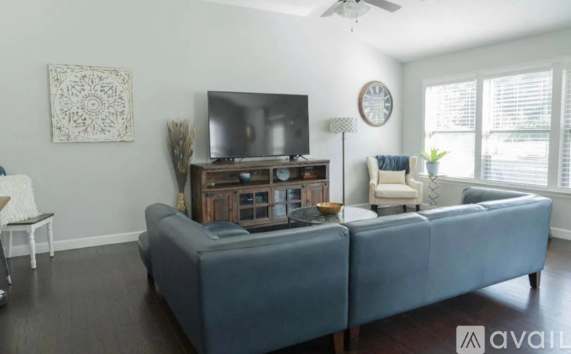 A living room with a grey sofa and a television on a wooden stand.