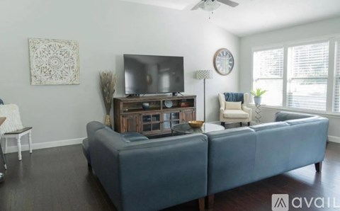 A living room with a grey sofa and a television on a wooden stand.