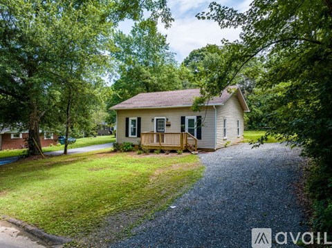 A house with a gravel driveway is surrounded by trees.