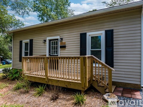 A small house with a wooden deck and black shutters.