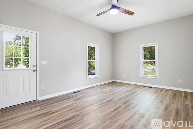 A room with a white door and two windows with a ceiling fan.