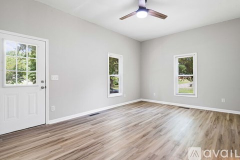 A room with a white door and two windows with a ceiling fan.