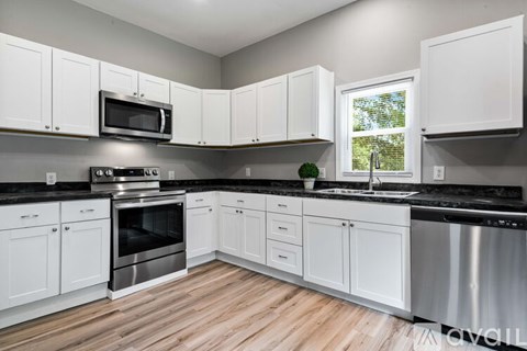 A kitchen with white cabinets and a black countertop.