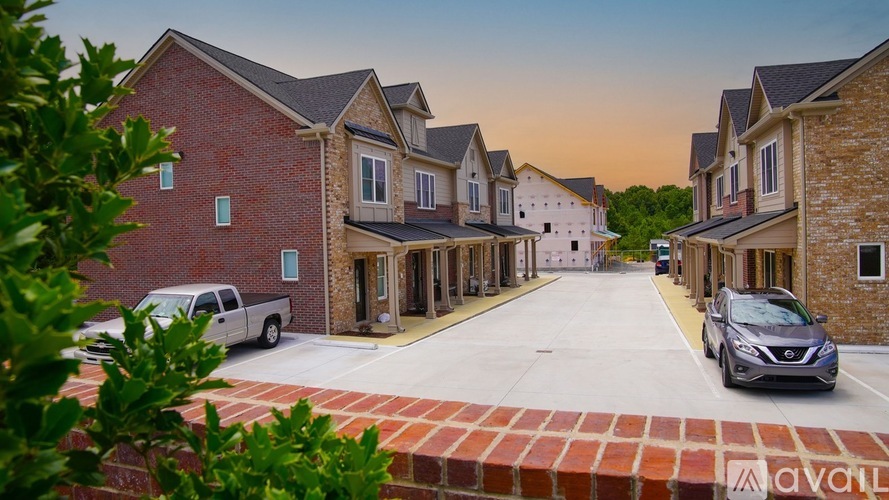 A row of houses with cars parked in front.