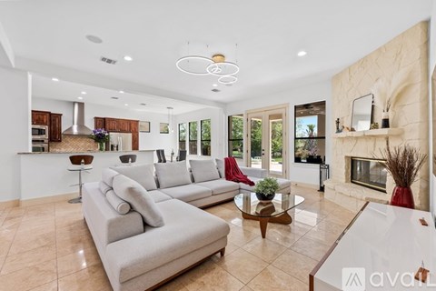 A spacious living room with a grey sofa and a glass coffee table.