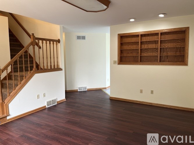 A room with wooden floors and a staircase on the left side.