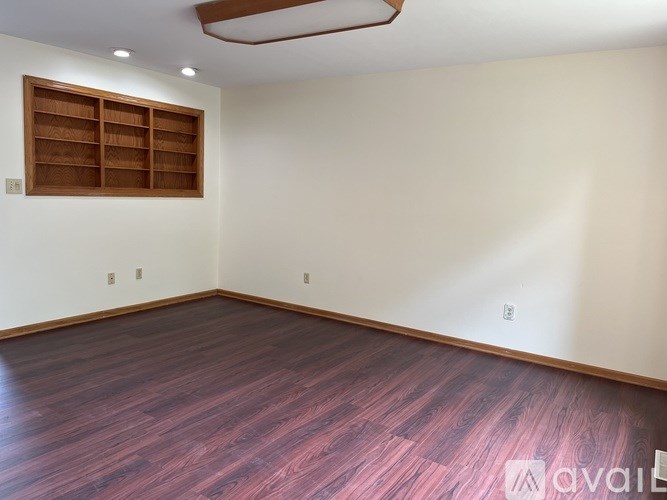 A room with wooden flooring and a window with wooden shutters.