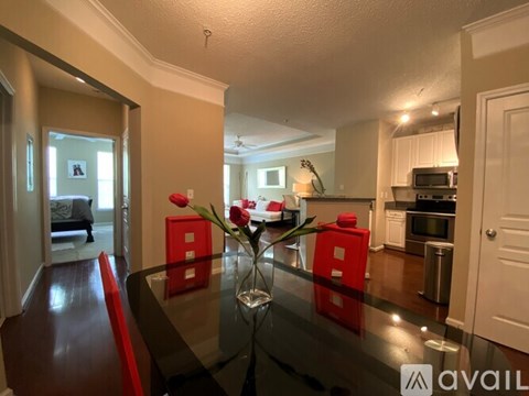 A dining room with a glass table and red chairs.