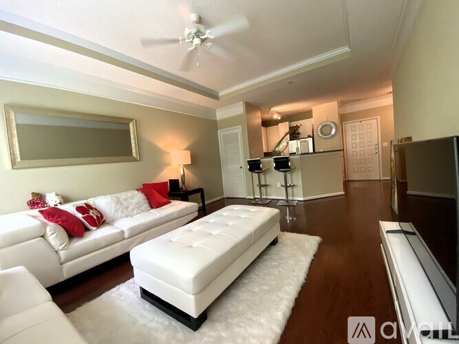 A living room with a white couch and a white ottoman.