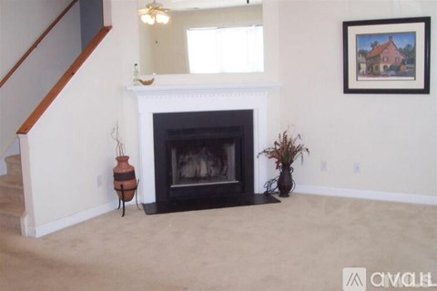 A living room with a fireplace and a painting on the wall.