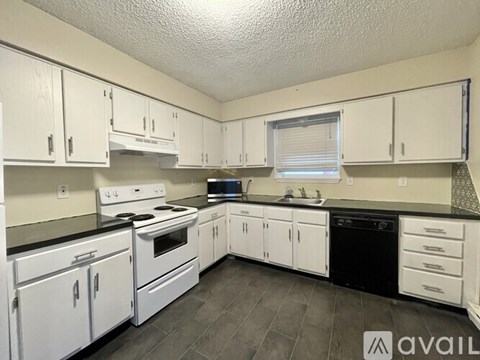 A kitchen with white cabinets and black countertops.