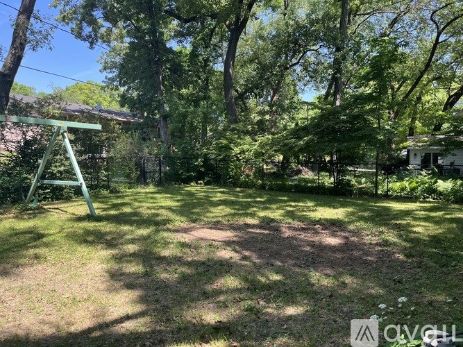 A backyard with a swing set and trees.