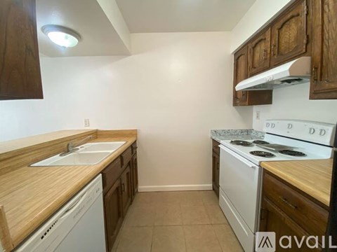 A kitchen with a white stove top oven and a white dishwasher.