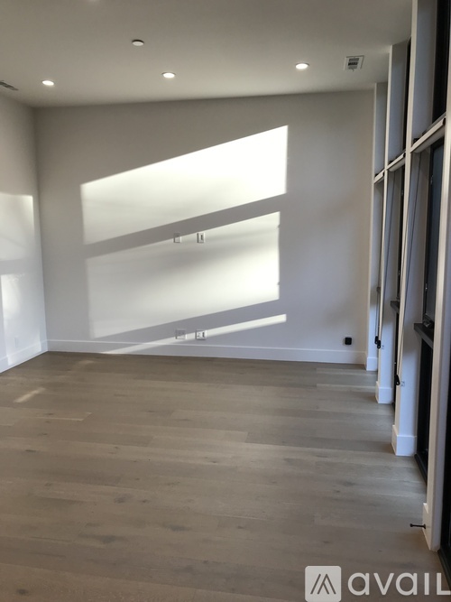 A spacious room with wooden flooring and a large window.