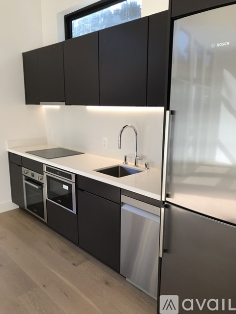A modern kitchen with black cabinets and stainless steel appliances.