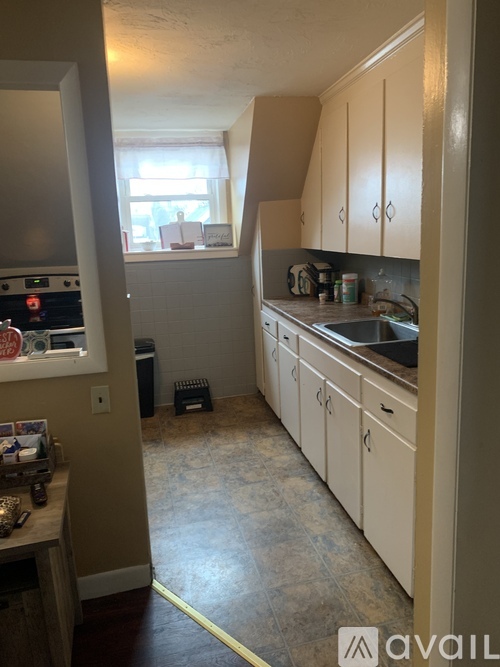 A kitchen with white cabinets and a tiled floor.