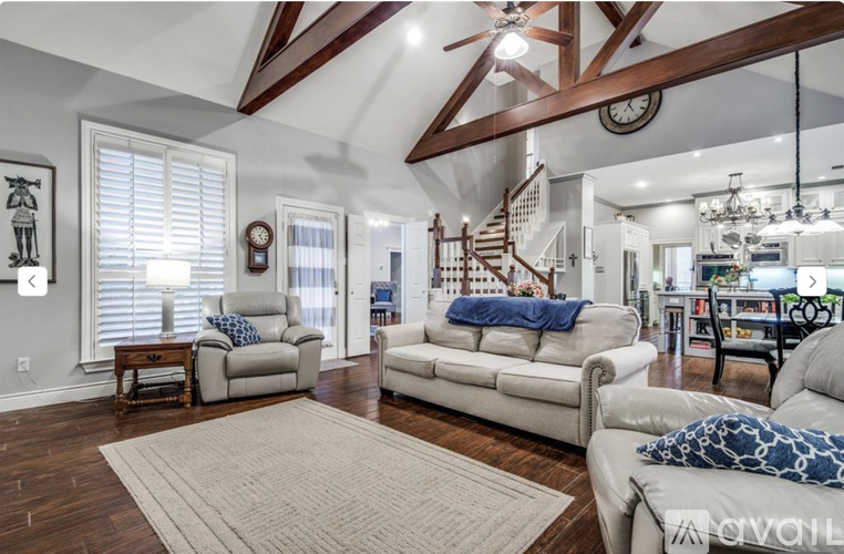 A living room with a white couch and a wooden staircase.
