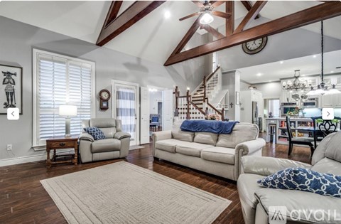 A living room with a white couch and a wooden staircase.
