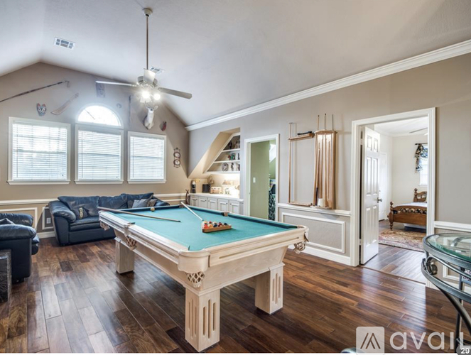 A pool table in a room with hardwood floors and a ceiling fan.