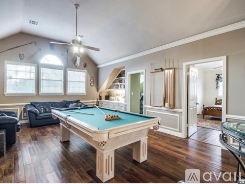 A pool table in a room with hardwood floors and a ceiling fan.