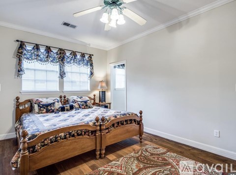 A bedroom with a large bed and a ceiling fan.