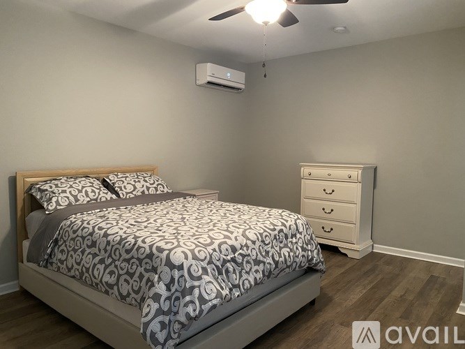 A bedroom with a bed, dresser, and ceiling fan.