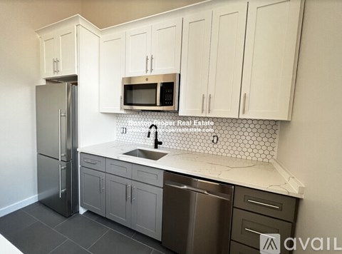 A kitchen with white cabinets and a stainless steel refrigerator.