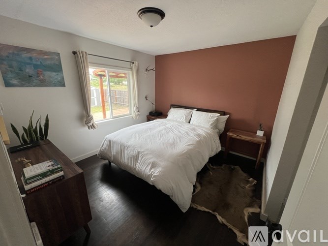 A bedroom with a white bed and a brown rug.
