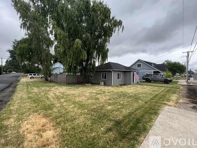 A house with a grey roof and a tree in front of it.