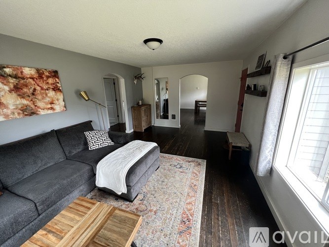 A living room with a grey couch and a rug.