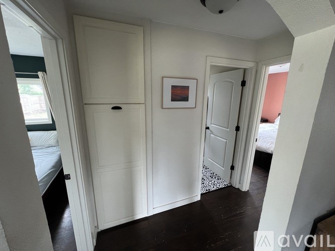 A room with a white door, a white cupboard, and a picture on the wall.