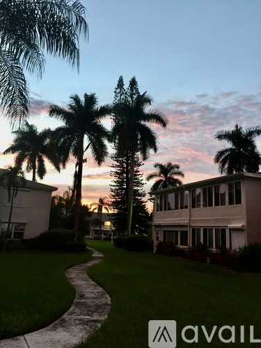 A house with a lawn and palm trees in front of it.