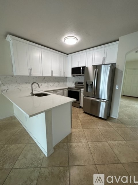 A kitchen with white cabinets and a marble countertop.