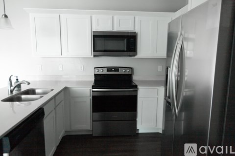 A kitchen with white cabinets and a black microwave above the stove.