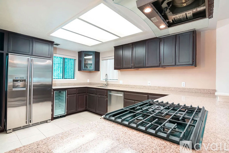 A kitchen with a refrigerator, cabinets, and a stove top.