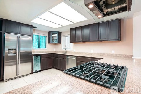 A kitchen with a refrigerator, cabinets, and a stove top.