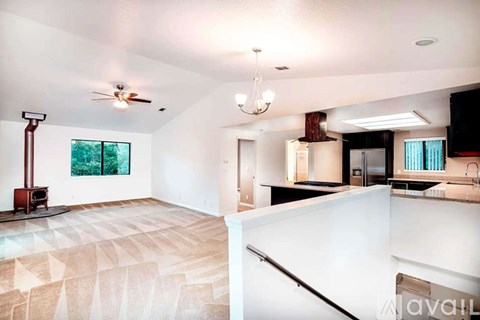 A living room with a wood stove and a kitchen area.