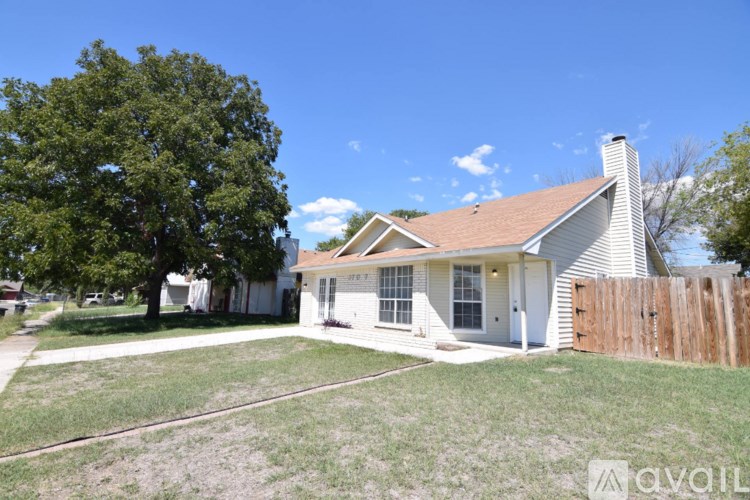 A house with a white exterior and a brown roof is surrounded by a wooden fence.