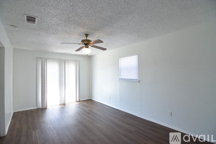 A spacious room with a ceiling fan and wooden flooring.