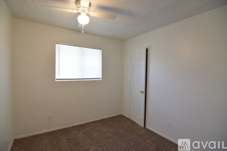 A room with a carpeted floor, a ceiling fan, and a window with blinds.