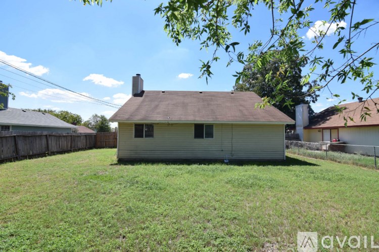 A house with a brown roof and a chimney is surrounded by a grassy yard.