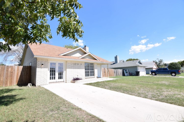 A house with a brown roof and a white fence is shown.