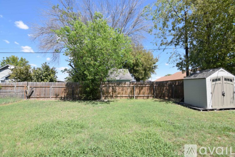 A backyard with a shed and a fence.