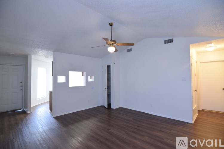 A room with a ceiling fan and wooden floors.