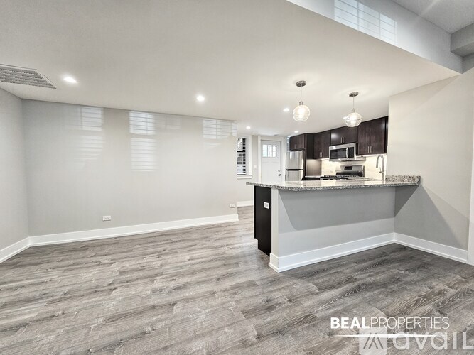 A spacious kitchen with a breakfast bar and grey flooring.