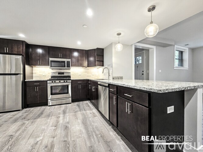 A modern kitchen with dark wood cabinets and stainless steel appliances.