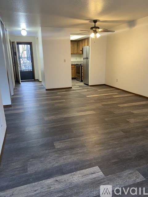 A spacious room with wooden flooring and a ceiling fan.