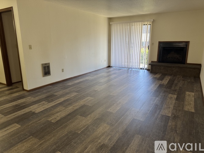 A spacious room with a fireplace and wooden flooring.
