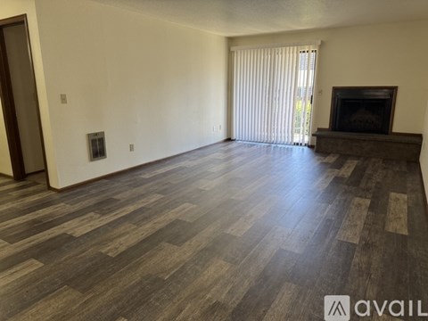 A spacious room with a fireplace and wooden flooring.